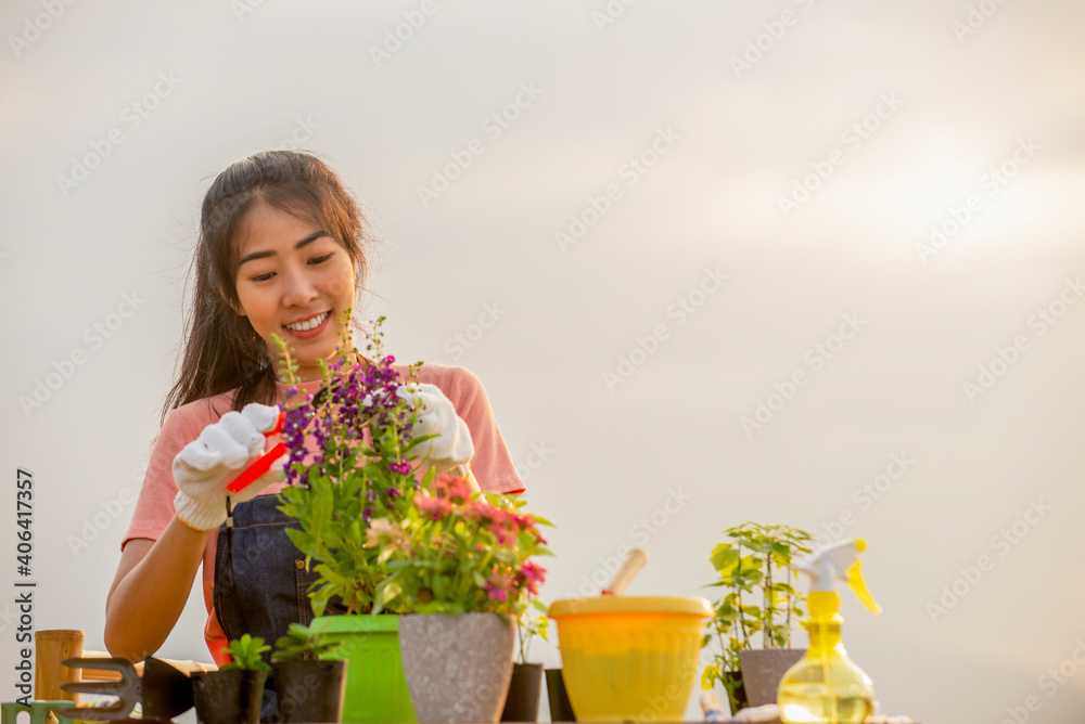 Portrait of smiling  young asian woman with  glove planting flower  in garden at outdoor