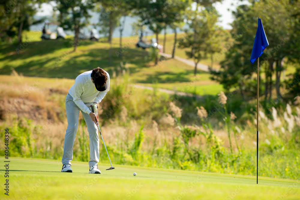 亚洲男子高尔夫球手手持高尔夫球杆，在高尔夫球场球道上击球至高尔夫球场