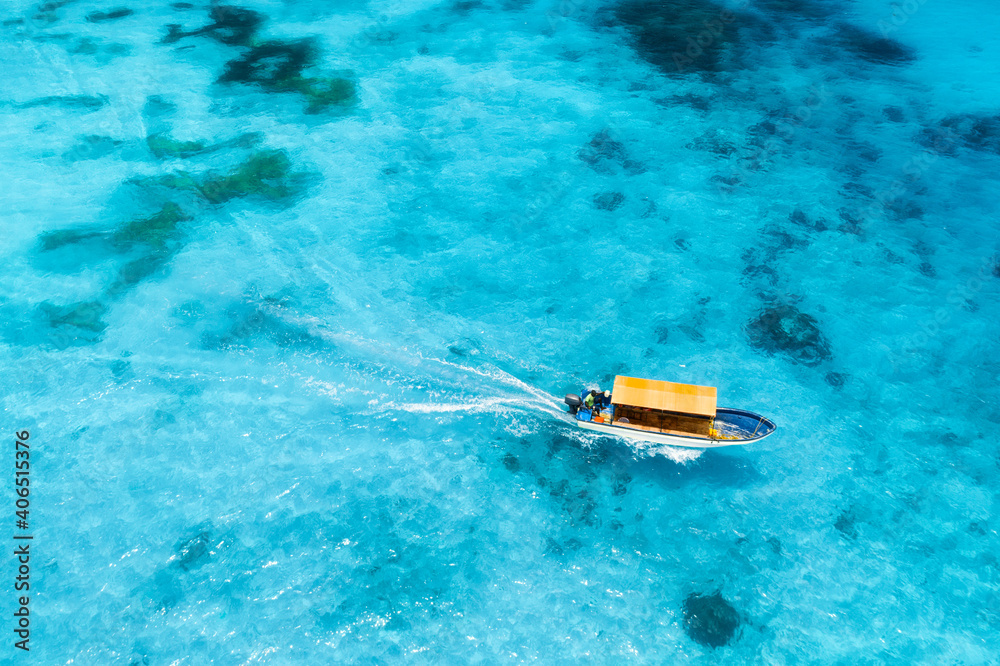 Aerial view of the fishing boat in clear blue water at sunset in summer. Top view from drone of yach