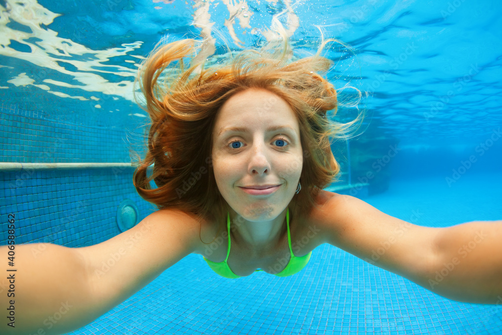 有趣的少女肖像。游泳，在蓝色游泳池里有趣地潜水——跳到水下深处。他