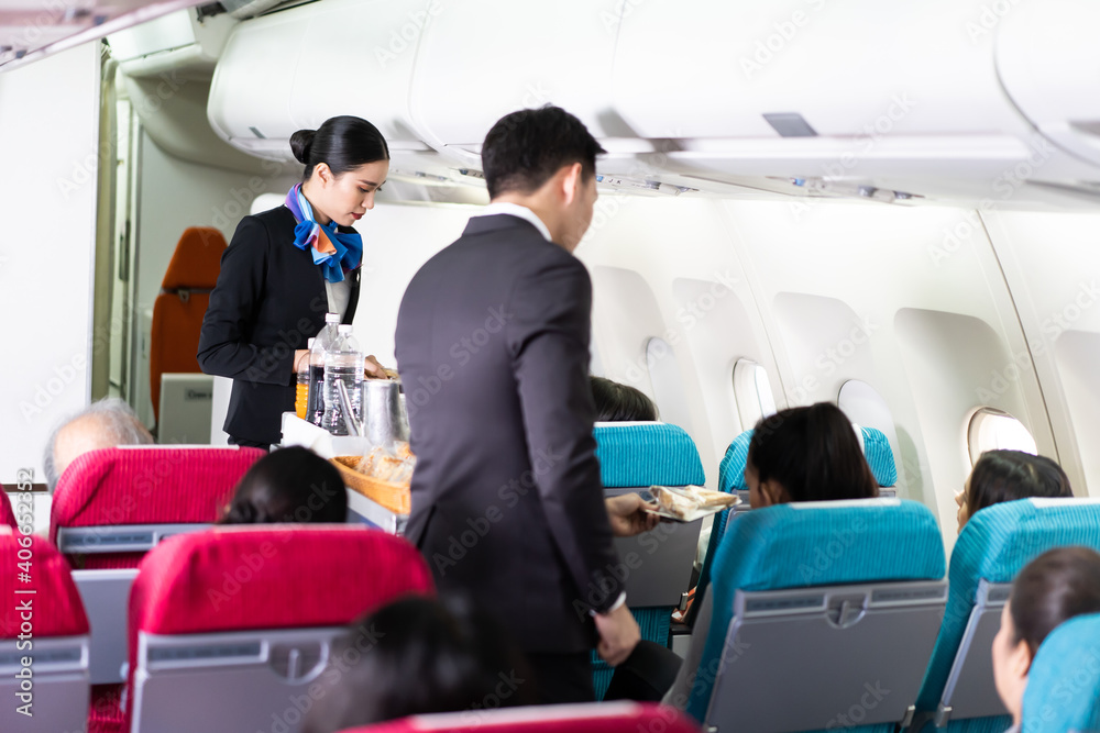亚洲空乘人员在飞机上为乘客提供食物和饮料