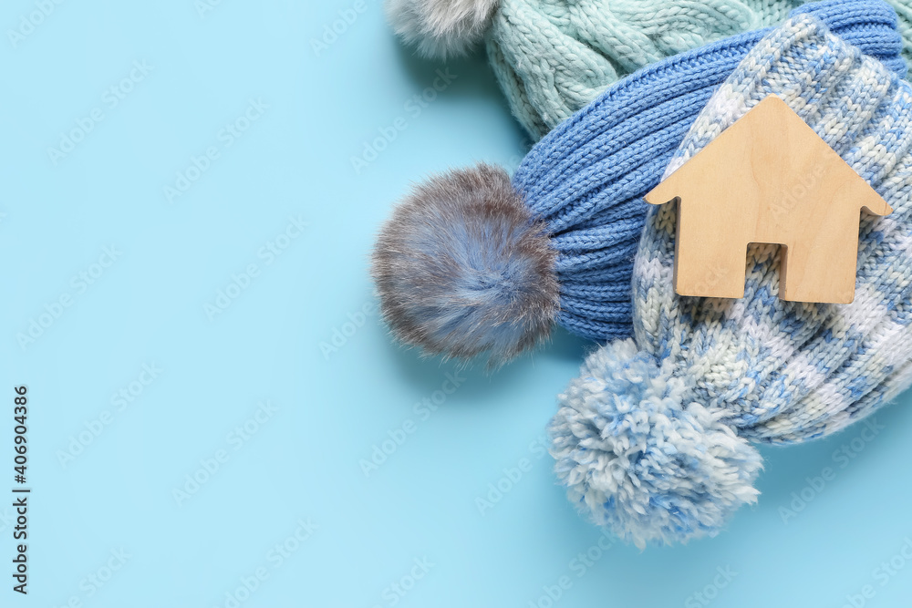 彩色背景上的房子和保暖帽的图案。供暖季节的概念