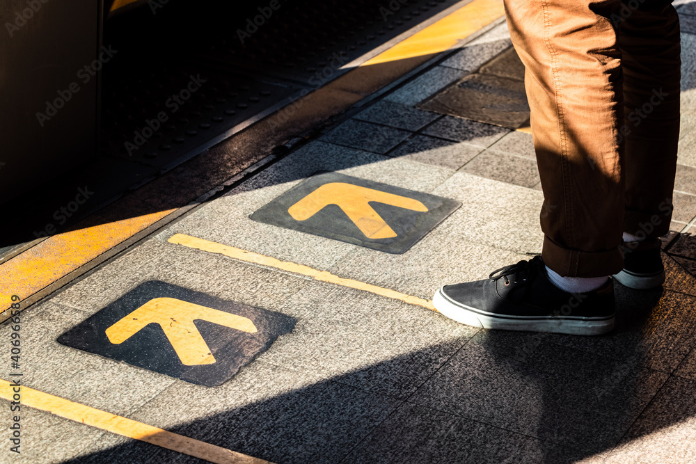 站在黄色箭头标志旁等待公共交通工具的男子。交通理念