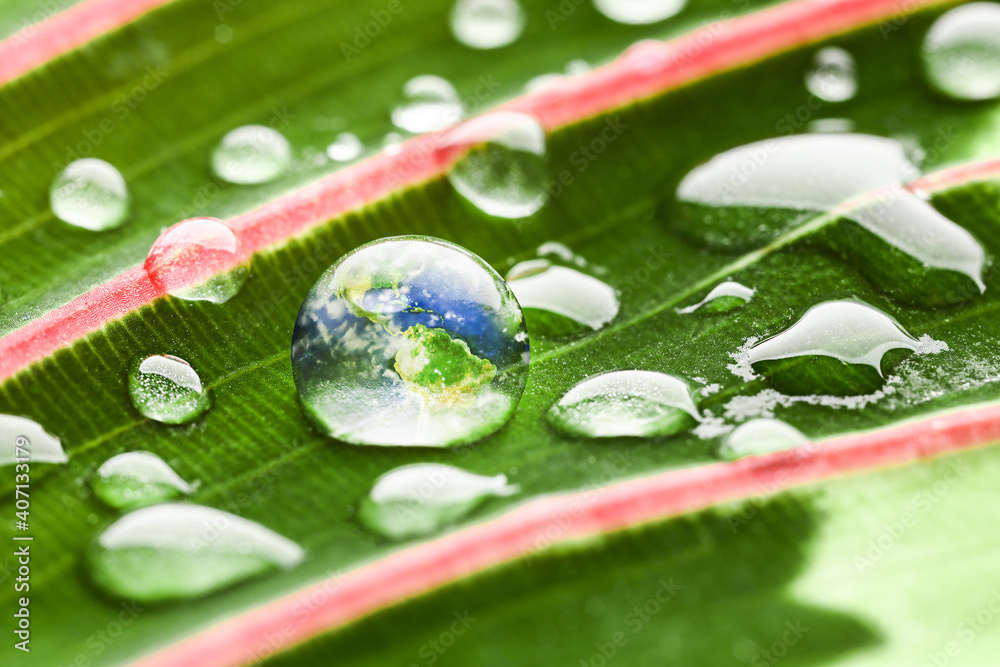Planet Earth inside of water drop on green leaf, closeup. Ecology concept