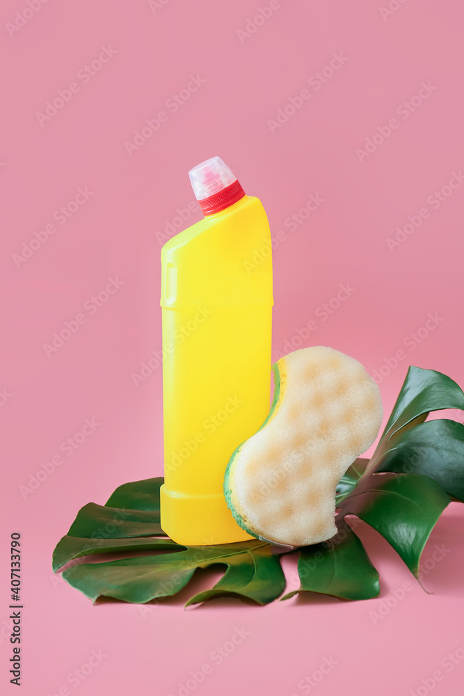 Detergent and cleaning sponge on color background