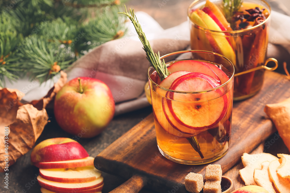 在木板上的玻璃杯中加入香料和苹果片的美味饮料