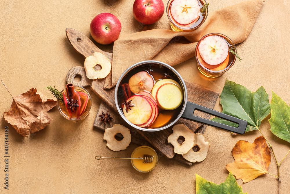 美味的饮料，在烹饪锅里放香料和苹果片，在彩色背景上放玻璃杯