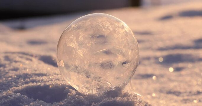 Soap bubble in the snow in winter. Ice patterns on the surface.