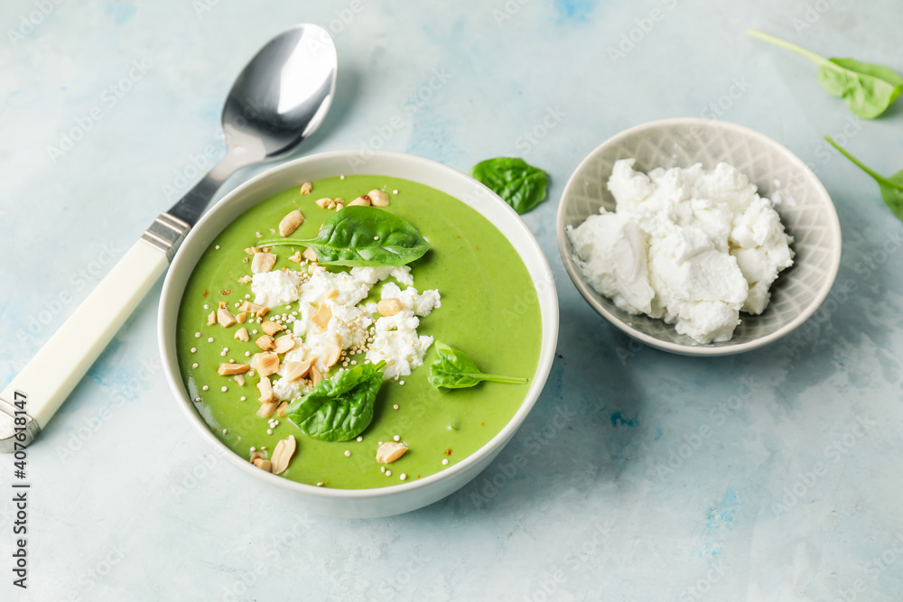 Bowl with tasty spinach soup on light background