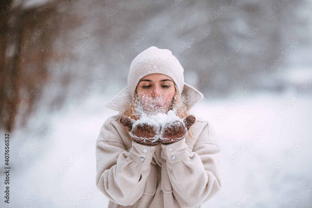 Winter woman blow snow while walk in the park