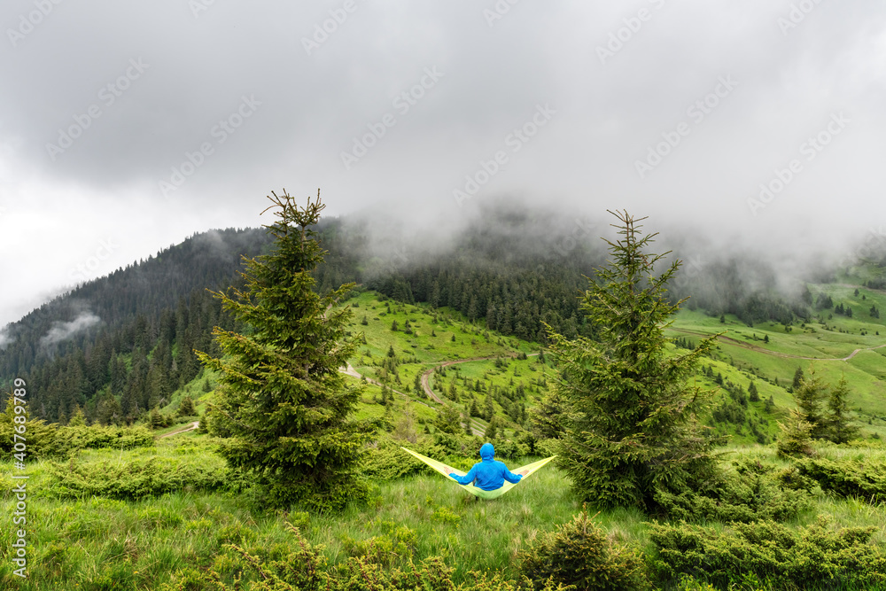 夏季山区黄色吊床上的男人。旅游景观概念。户外露营