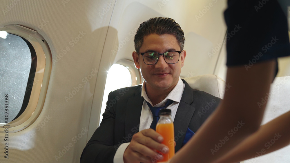 Businessman have orange juice served by an air hostess in airplane . Business trip travel concept .