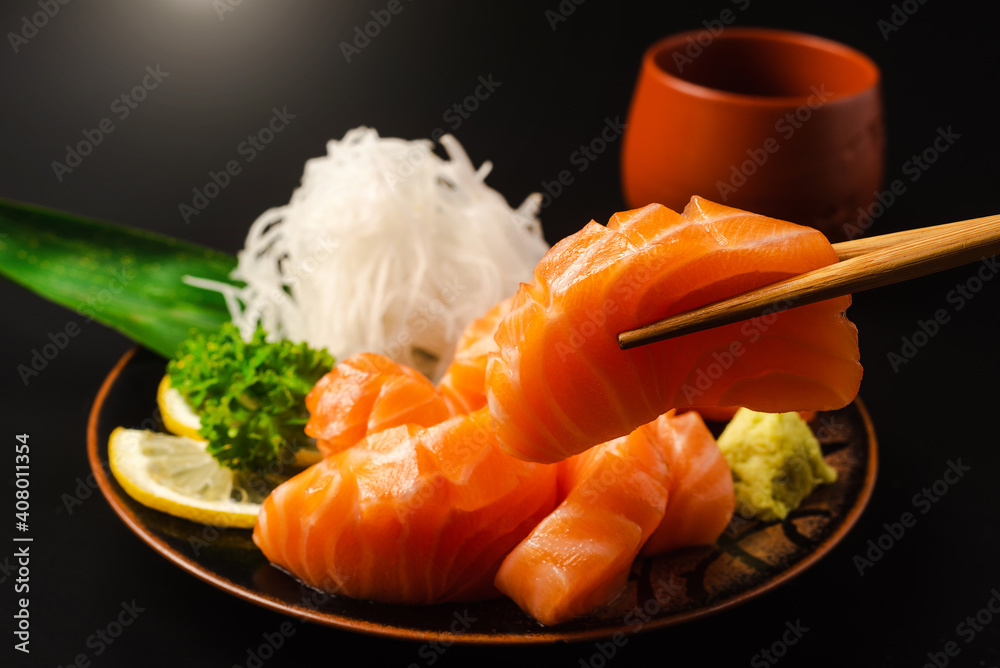 刺身、三文鱼、日式筷子和芥末配黑盘子
