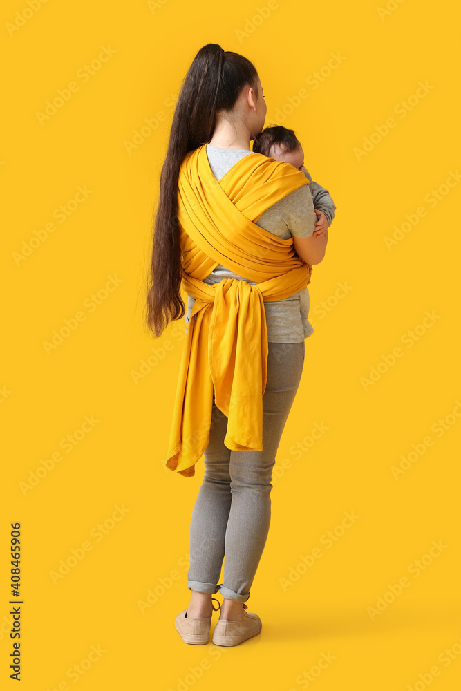 Young mother with little baby in sling on color background