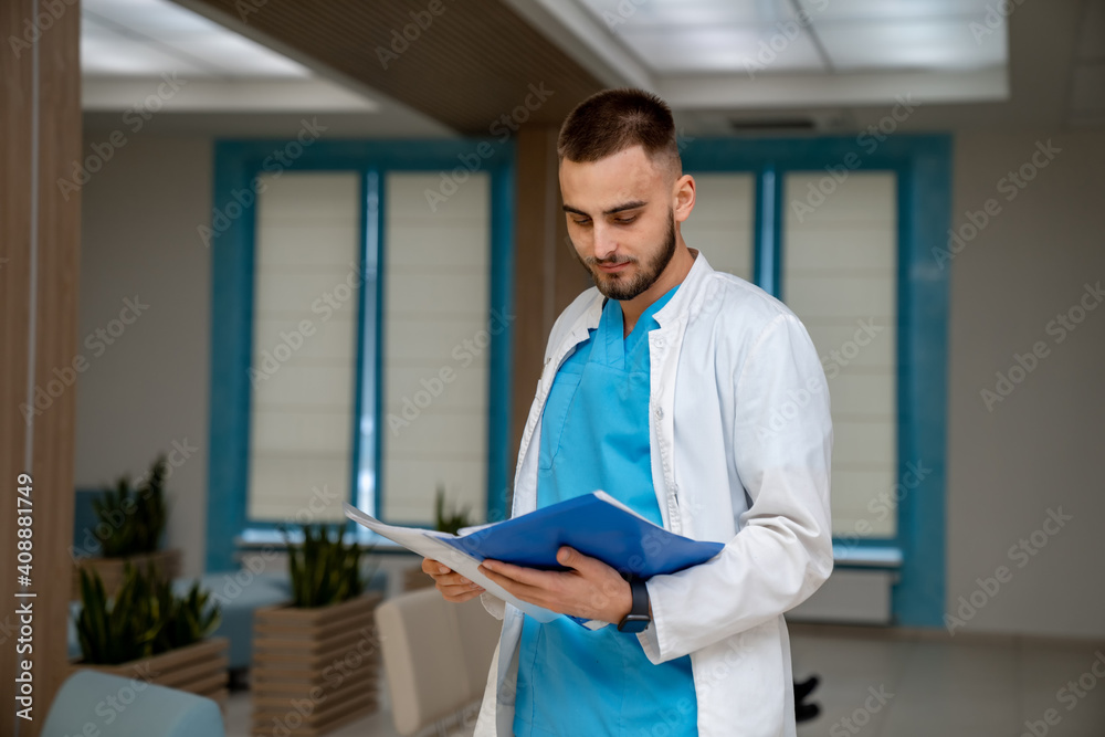A male doctor with a folder isolated on clinic background. Experienced medic with patient`s diagnosi
