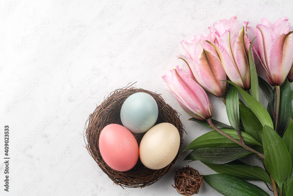 巢中有五颜六色的复活节彩蛋，上面有粉红色的双百合花。