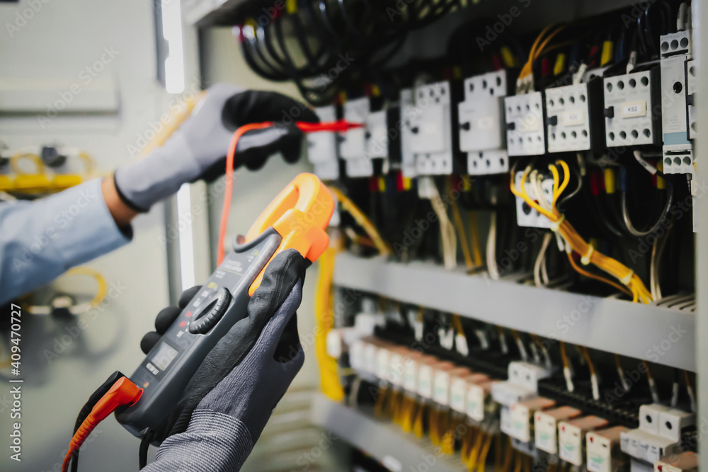 电气工程师测试保护继电器上的电气装置和接线，并对其进行测量。
