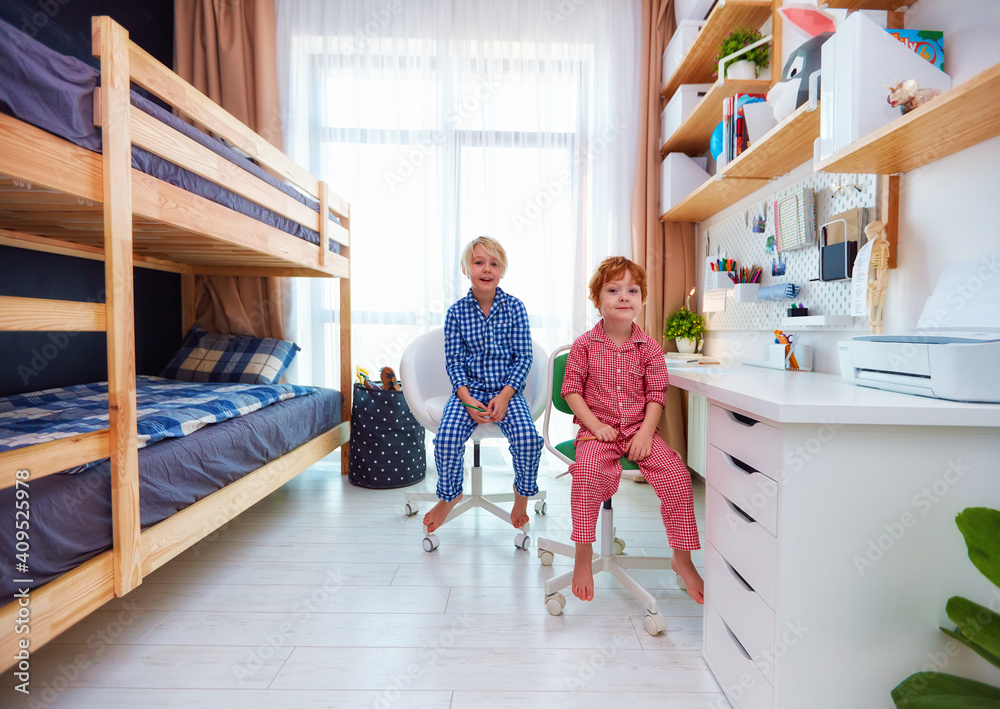 两个男孩的共享儿童卧室，配有双层床、大桌子和墙架