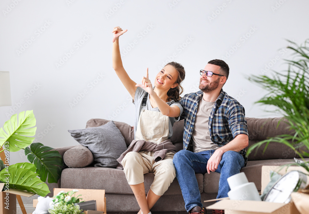 微笑的夫妇带着盒子坐在新公寓里