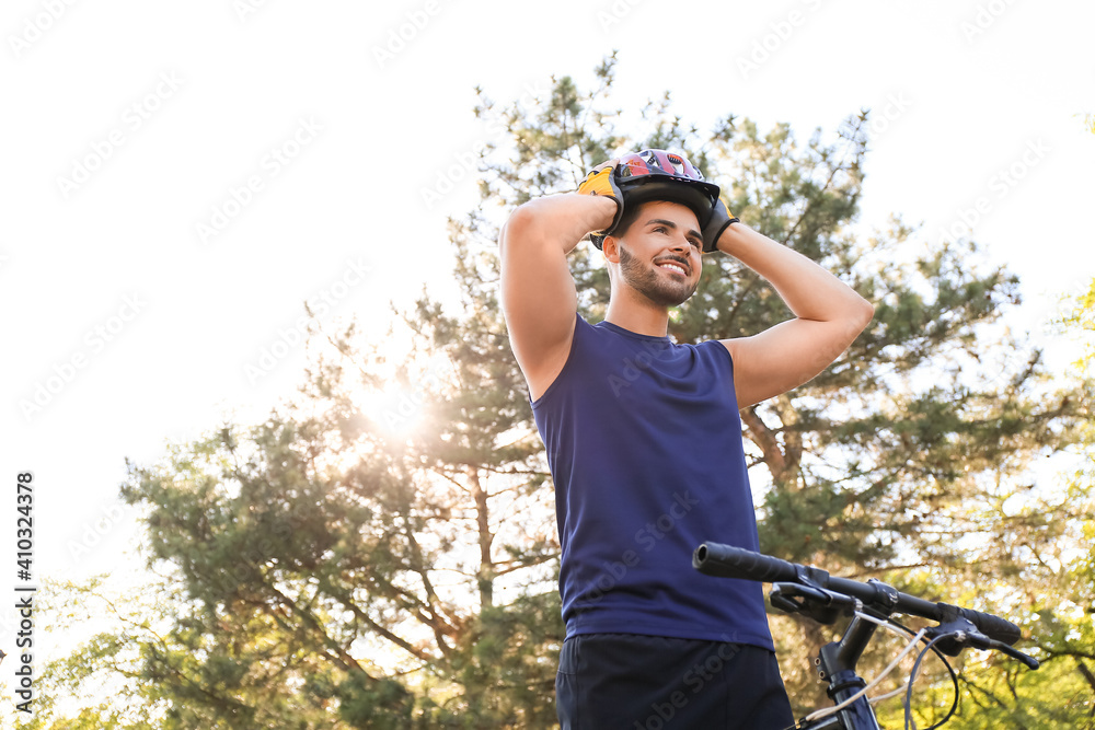 Male cyclist putting on helmet outdoors