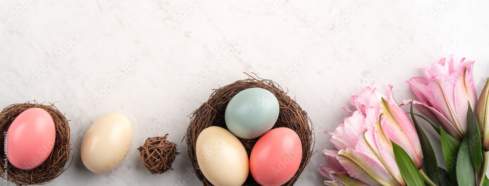 巢中有五颜六色的复活节彩蛋，上面有粉红色的双百合花。