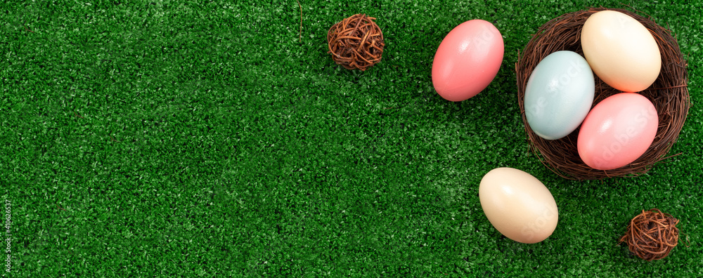 草坪上的鸟巢里有五颜六色的复活节彩蛋，上面开着粉红色的双百合花。