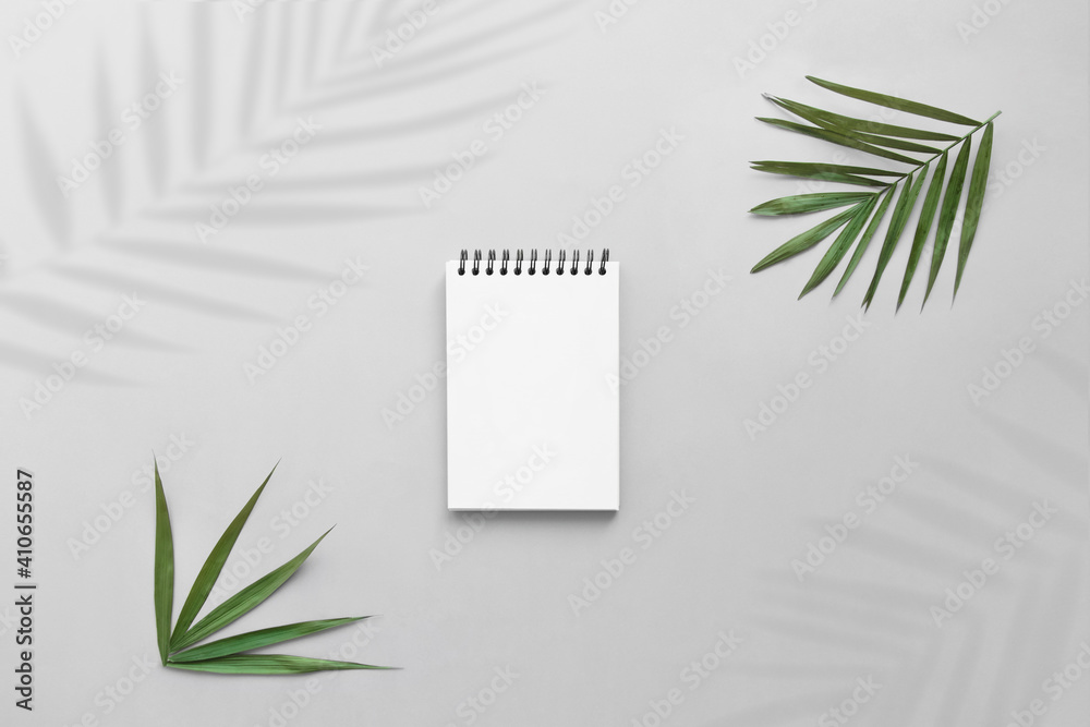 Notepad on gray desk with shadows of palm leaves