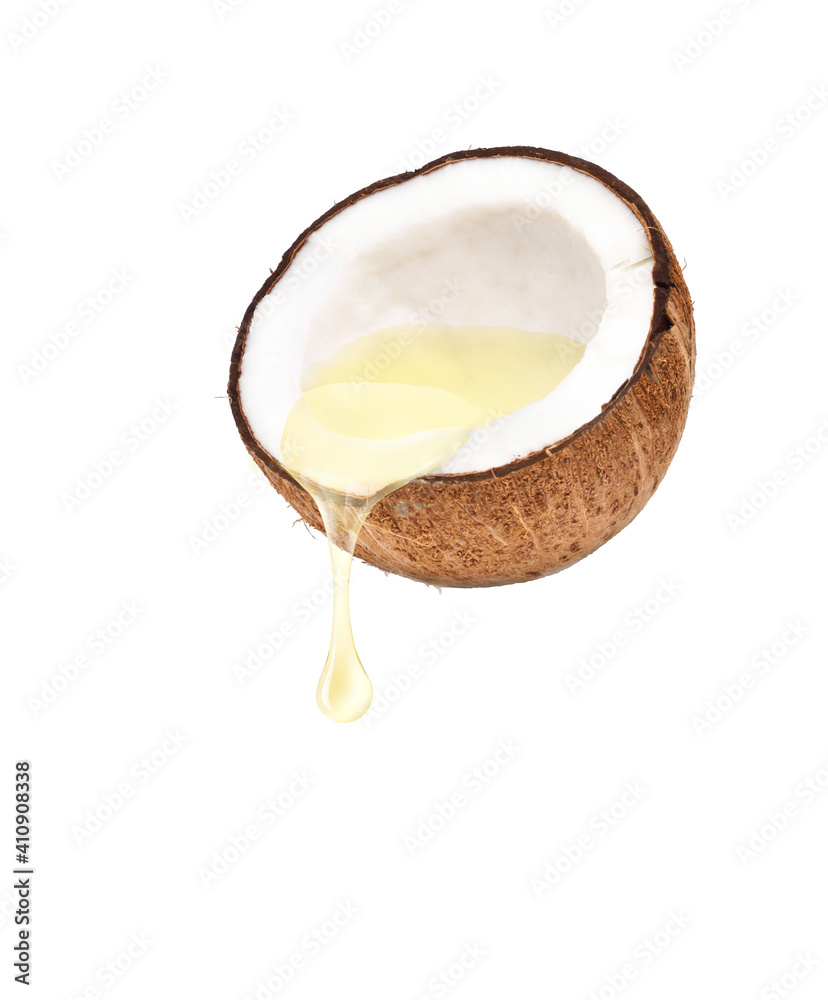 椰子油从切成两半的椰子果实滴落，白色背景。