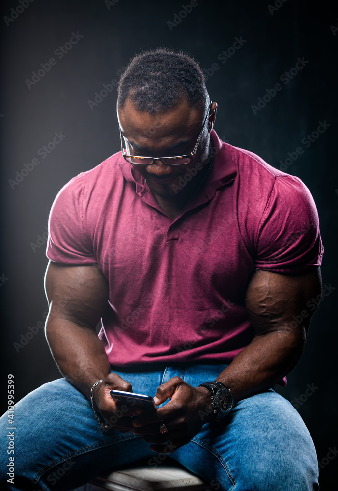 细心的英俊男子靠着头在手机上读东西。男性坐在高脚椅上，带着b