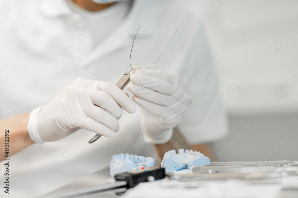 牙科技师与一个牙齿模型一起工作，尝试正畸治疗的支架系统