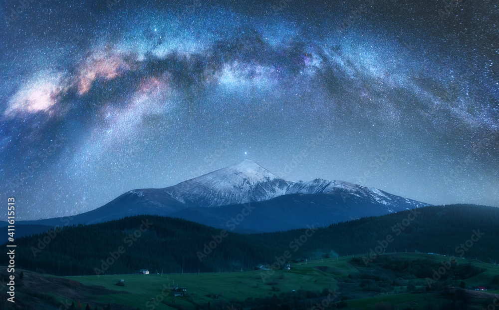在夏天的夜晚，银河在美丽的山脉上拱起，山峰被雪覆盖。五颜六色的la