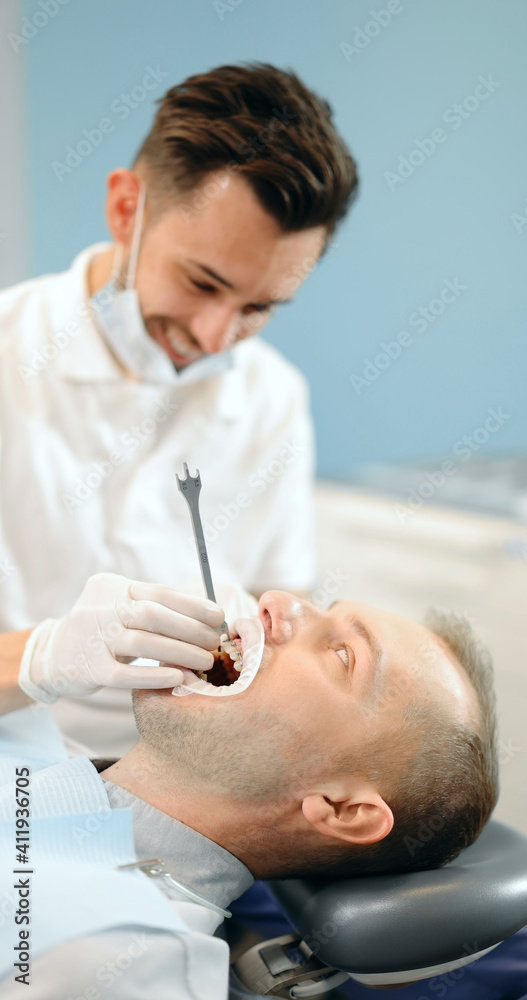 牙医在年轻男性患者的正畸治疗中调整牙套。4k视频sc