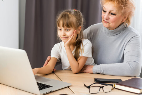 Grandmother with granddaughter use laptop learn counting together home