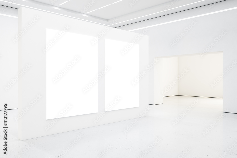 在空荡荡的宽敞灯光厅的白墙上贴着两张白色空白海报，天花板上有led灯。Mocku