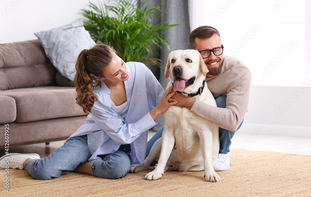 幸福的已婚夫妇在家里和他们最喜欢的宠物狗玩耍