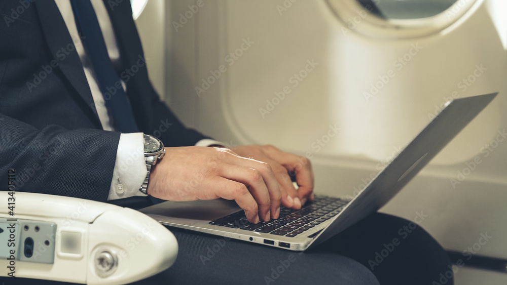 年轻商人在飞机上使用笔记本电脑。商务旅行概念。