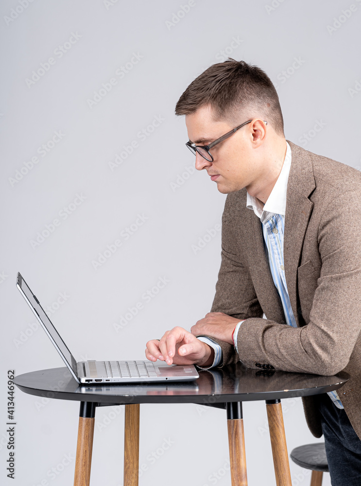 戴眼镜的年轻人在笔记本电脑上工作。男性在一天的早些时候就把生意做好了。M