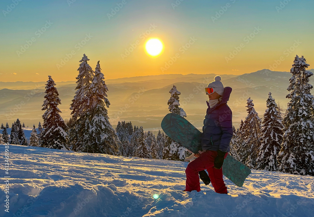特写：日落时分，年轻的女单板滑雪运动员在没有房间的雪坡上徒步旅行。