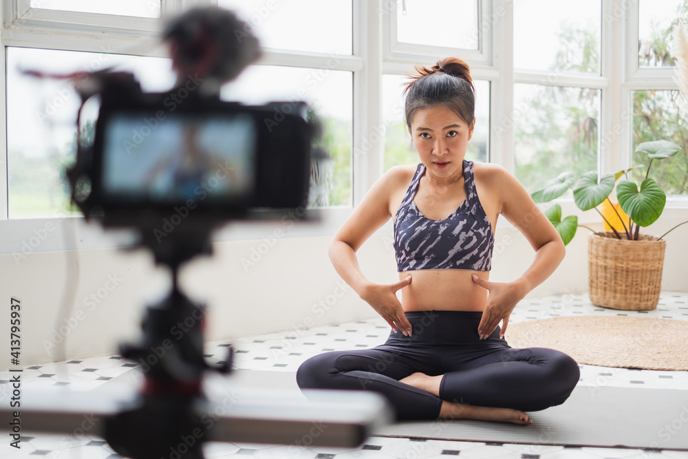 Asian woman trainer making online live streaming training and show how to exercise workout, yoga at 