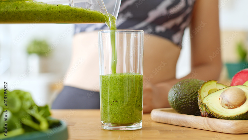 运动女性用搅拌机制作健康的绿色新鲜奶昔，用于健康饮料，包括蔬菜a