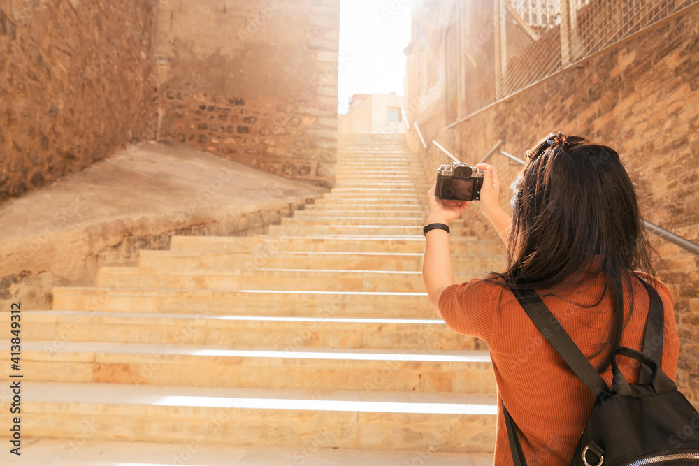 迷人的亚洲女性旅行者旅游手用相机观光车里的旧石头楼梯走廊