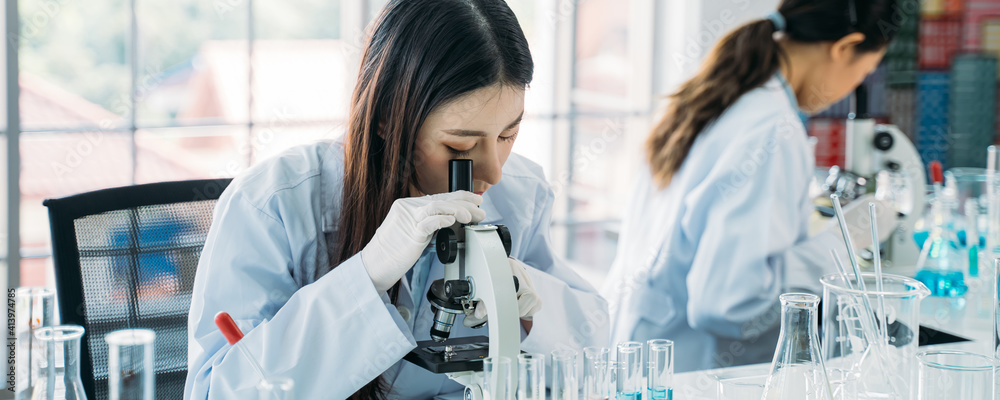 与同事一起穿着实验室外套和手套在实验室进行研究的年轻亚洲女科学家