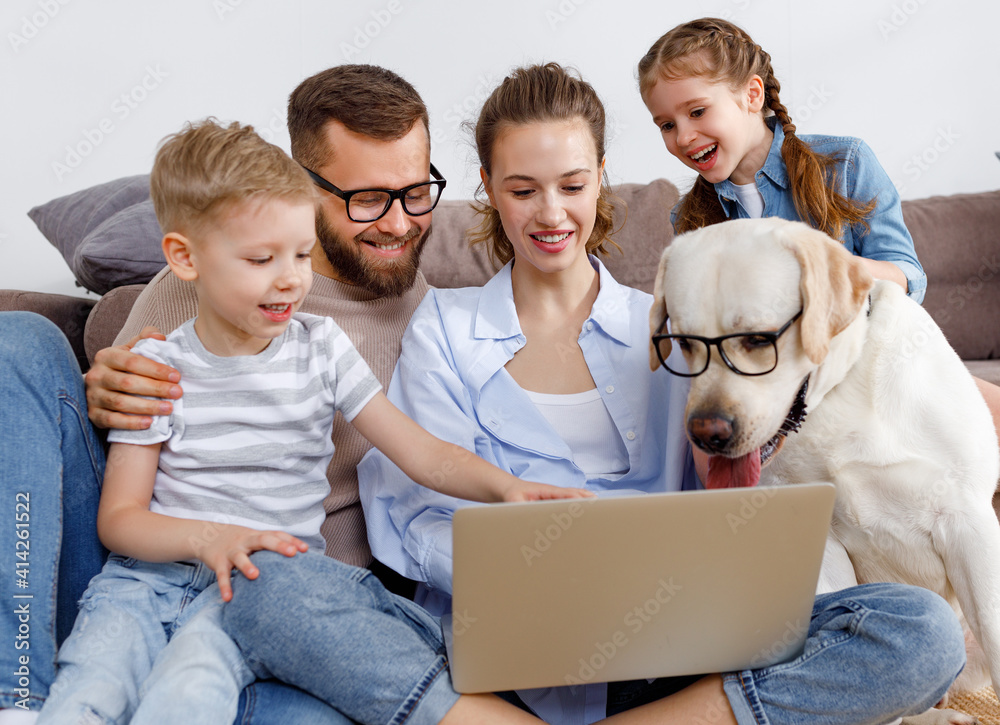 快乐的父母带着孩子和狗在笔记本电脑上看电影