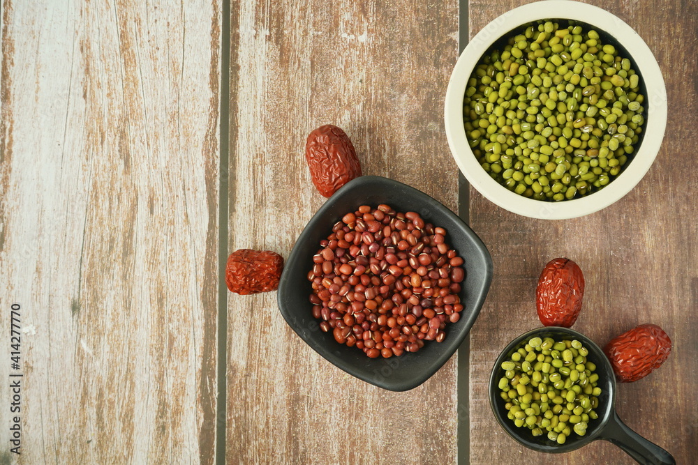 装在旧木桌上的容器里的绿豆、红豆、红枣，俯视图，健康饮食