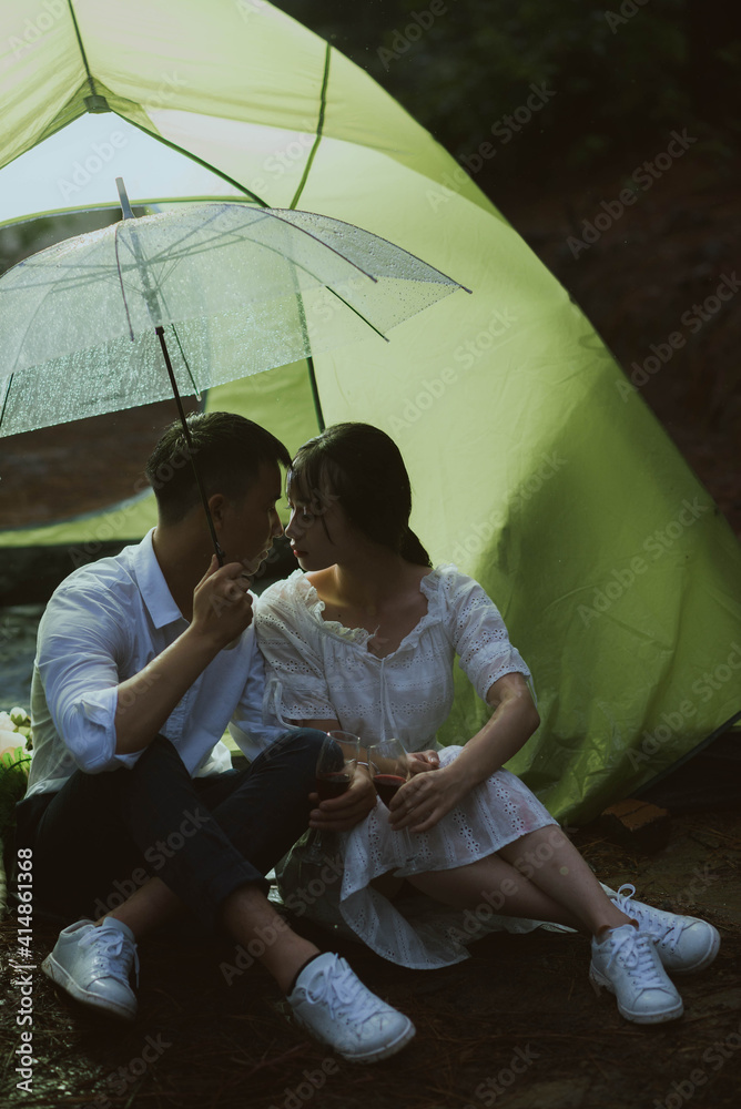 年轻的亚洲情侣在雨中接吻