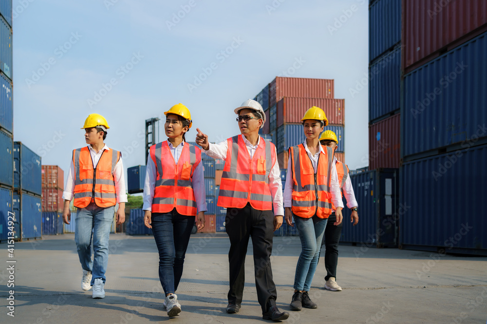 Asian foreman walking and explaining the various operations in the container depot terminal with fou