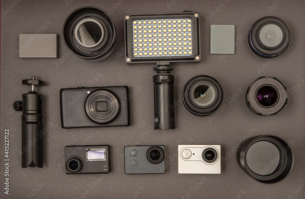 A set of lenses, action cameras and other photographic equipment on a dark gray background.