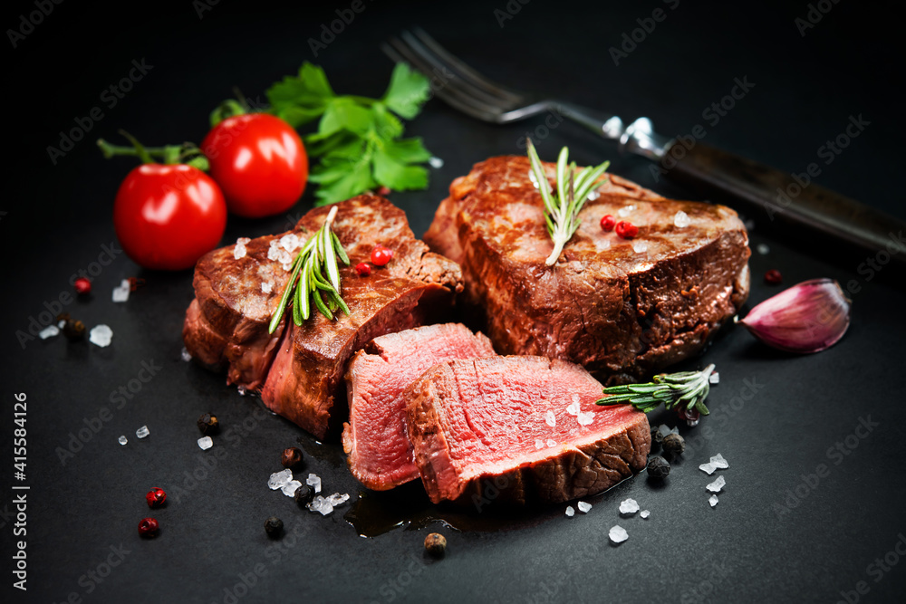 Grilled beef filet steaks with herbs and spices on dark slate