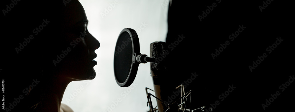带录音室麦克风的女性剪影。头和肩膀侧面照片。歌唱概念。白色