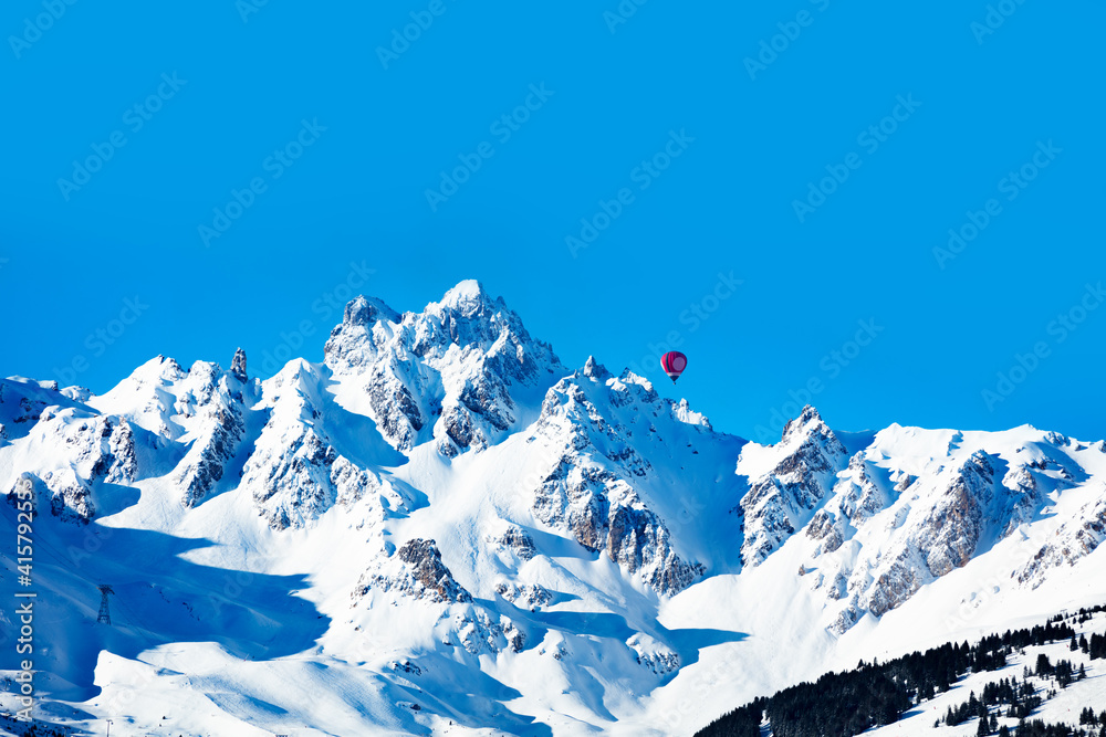 阳光明媚的冬日，红色鲜艳的热气球飞越法国阿尔卑斯山山谷